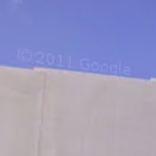 a screenshot of google streetview; a corner of a roof and blue sku. they look like an astronaut. copyright google is across the image